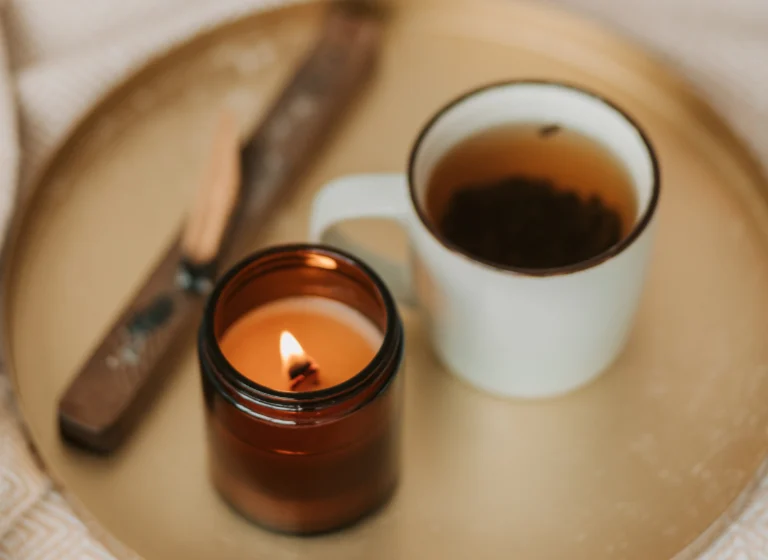 Aesthetic stock image shows a bronze-plated tray with a lit candle, herbal tea and incense sticks. The image is purely for decorative use only to support the blog post on autumn self-care ideas to fall in love with this season