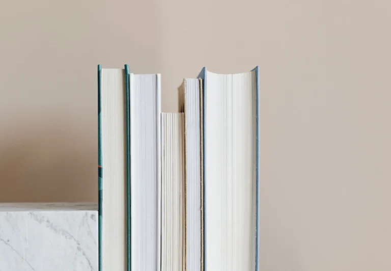Aesthetic stock image of a stack of books up against a rose pink wall. Image is purely for decorative use only to support the blog post on the benefits of reading in the morning