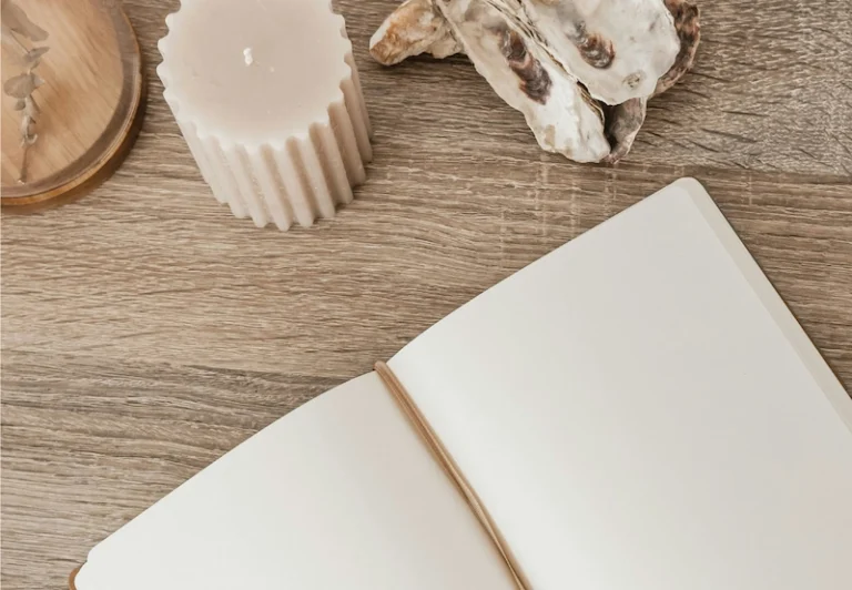 Aesthetic stock image showing an open notebook on a table with a mug of coffee. The image is purely for decorative use only to support the blog post on becoming your best self; 101 journal prompts for self-reflection