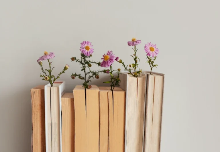 Aesthetic stock image showing a stack of books lined up in front of a white wall. The image is purely for decorative us only to support the blog post on the books I’m reading this summer.
