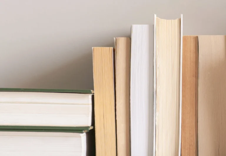 Aesthetic stock image showing a stack of books with their spines up against the wall. The image is purely for decorative use only to support the blog post on the 7 best books to survive the the 9-to-5 corporate grind