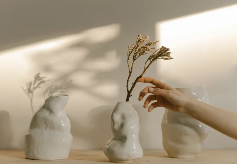 Aesthetic stock image showing a women’s hand touch an indoor plant in front of a white wall. The image is purely for decorative us only to support the blog post on how to break up with the hustle culture.