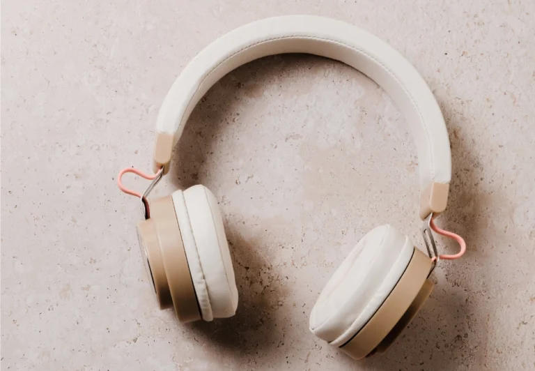Aesthetic stock image shows a retro pair of headphones against a light pink marble table. The image is purely for decorative use only to support the blog post about how to tap into your inner child and find joy
