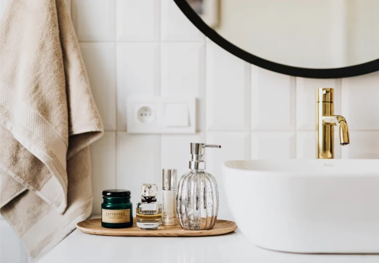 Aesthetic stock image showing numerous skin care products around a white sink with bronze. The image is purely for decorative use only to help support the blog post on morning routine ideas