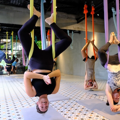 Lifestyle picture taken of Thalia, the author of Notes by Thalia, showing her hanging upside down while doing aerial yoga