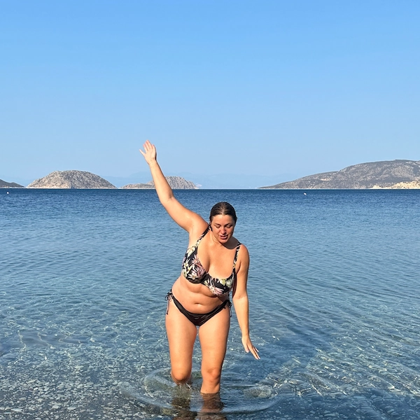 Recent picture of Thalia, author of Notes by Thalia taken in September 2024 walking out of the sea with right arm in the air in Greece