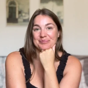 Professional headshot taken of the author of Notes by Thalia, Thalia posing to the camera with a smile and her hand resting on her chin