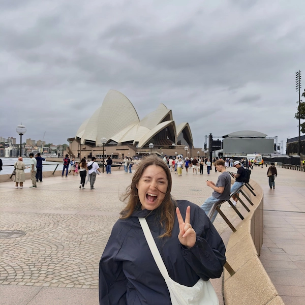 Lifestyle photo showing the author of Notes by Thalia, Thalia posing in front of the Sydney opera house on a cloudy and windy day