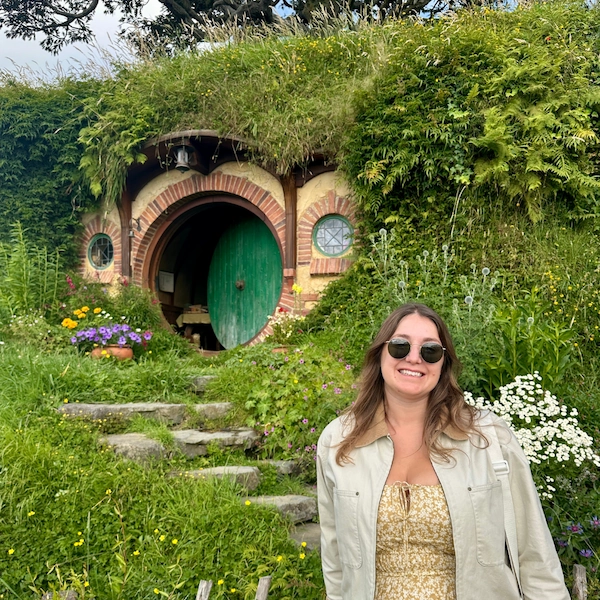 Lifestyle photo showing the author of Notes by Thalia, Thalia posing in front of a hobbit house in Hobbiton, New Zealand