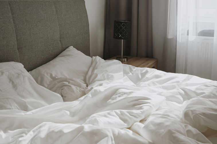 Aesthetic stock image showing an unmade bed with white sheets and pillows. The image is purely for decorative us only to support the blog post on things you can do instead of bed rotting.