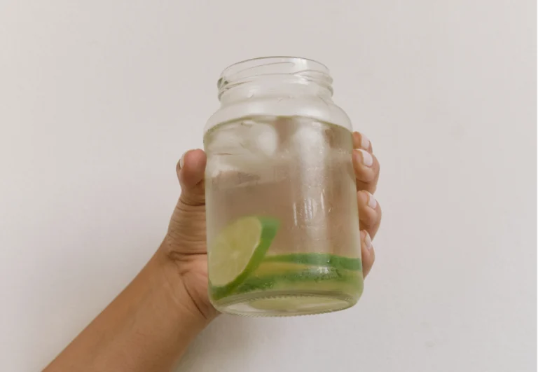 Aesthetic stock image of a female hand holding a glass of water with limes. The image is purely for decorative use only to support the blog post on how to start a wellness journey