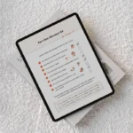 iPad device showing a page from the Stay & Slay Workbook. The iPad is lying on a white boucle sofa