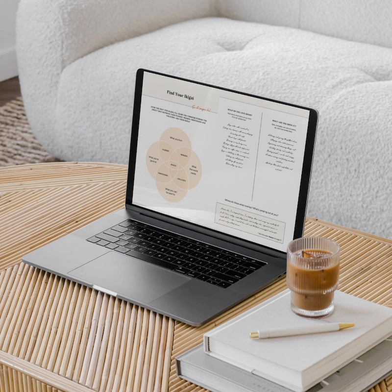 A laptop showing two pages from the Stay & Slay Workbook. The laptop is open on a brown coffee table